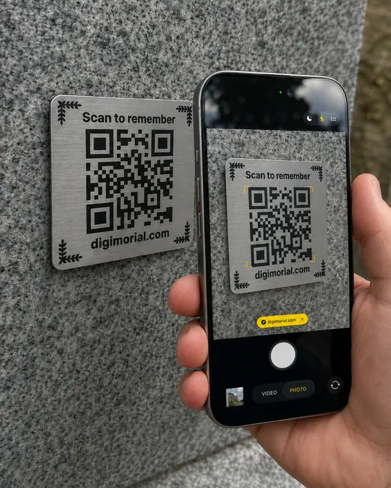 Phone scanning a Digimorial QR code plaque on a headstone